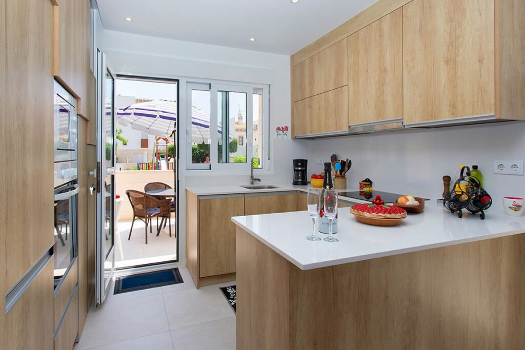 Mobiliario de cocina de alta gama con isla lacada en blanco y una elegante barra de madera natural adosada para comidas rápidas