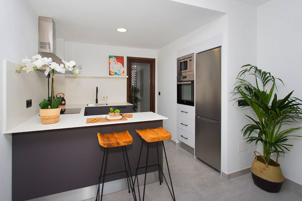 Diseño vanguardista de una cocina de lujo con una gran isla central en color gris antracita, encimera blanca pulida y revestimientos de madera cálida