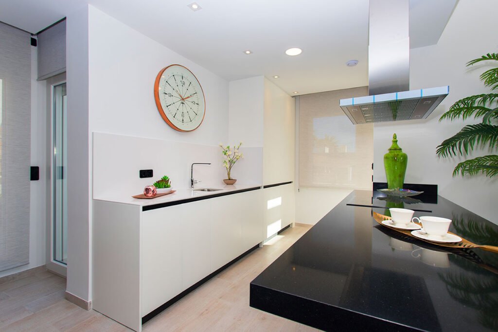 Estudio visual de una cocina premium destacada por una imponente isla de granito negro mate, taburetes elegantes y acabados de revista
