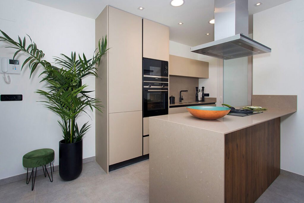 Distribución óptima en cocina moderna con columnas de almacenaje en madera, electrodomésticos integrados en torre e isla blanca central