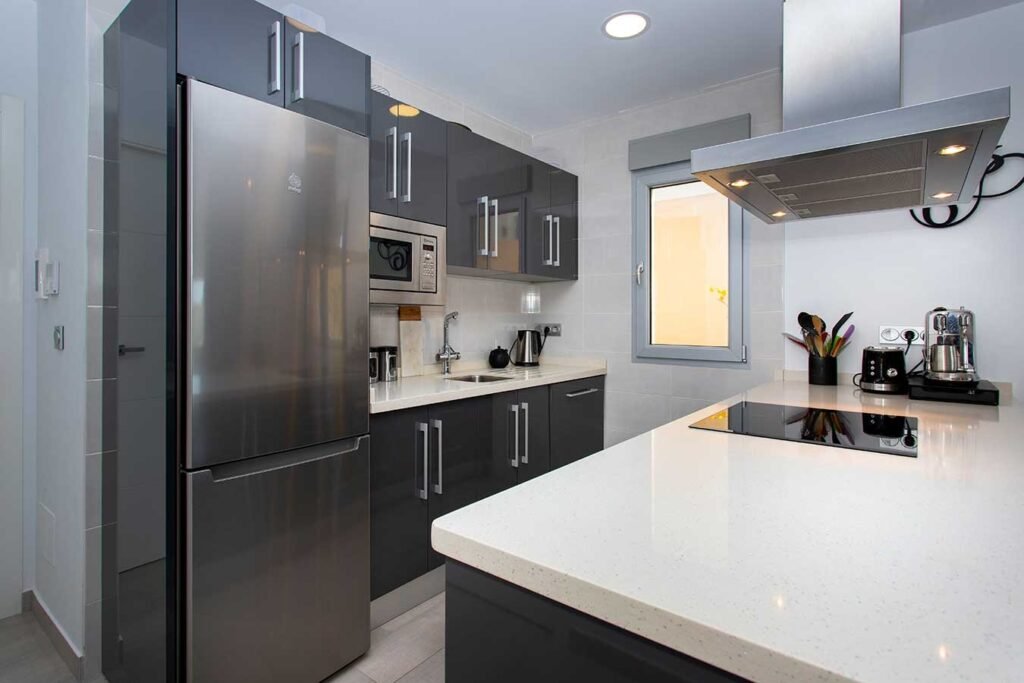 Vista amplia de una cocina de concepto abierto integrada con el salón, isla central con encimera gris y sutiles lámparas colgantes