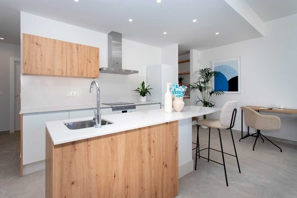 Decoración de cocina actual que fusiona armarios de madera natural con acabados en blanco puro y una práctica barra de desayuno