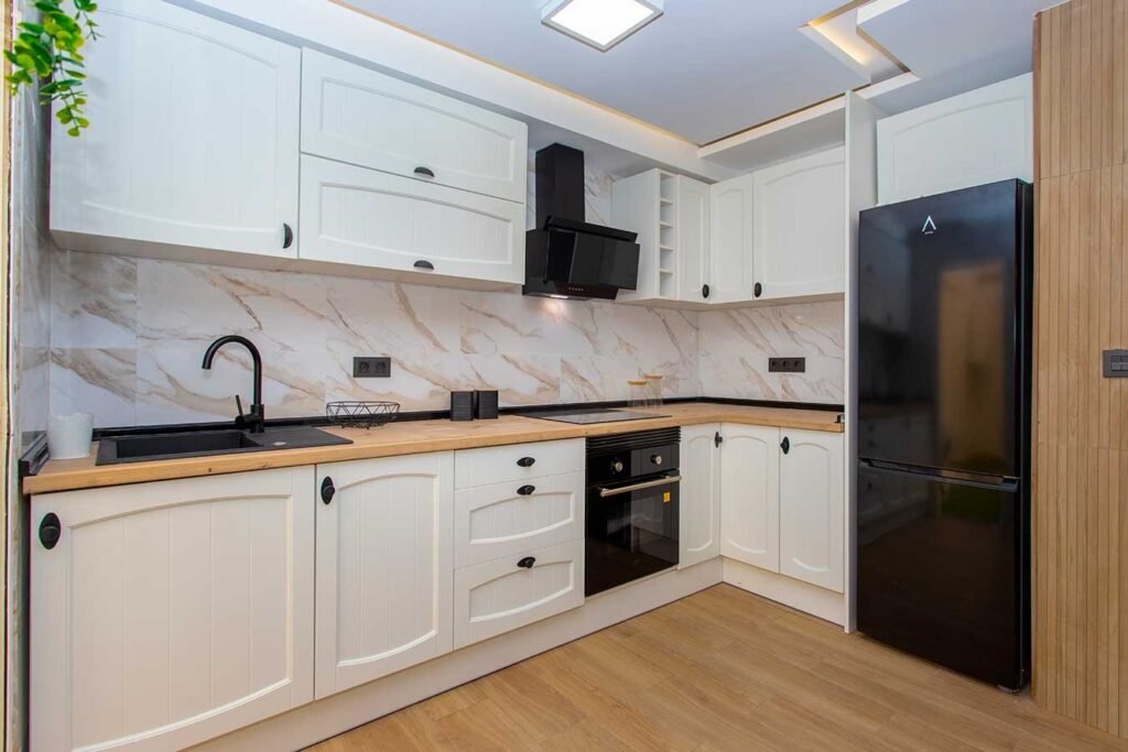 Fotografía inmobiliaria de una cocina moderna con distribución en L, encimera texturizada de madera e iluminación LED bajo los armarios
