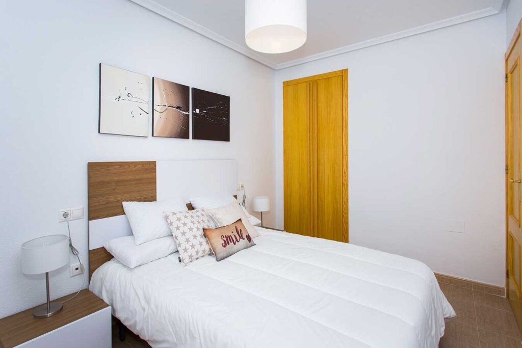 Fotografía profesional de un dormitorio matrimonial moderno en tonos blancos con iluminación LED sutil en el techo