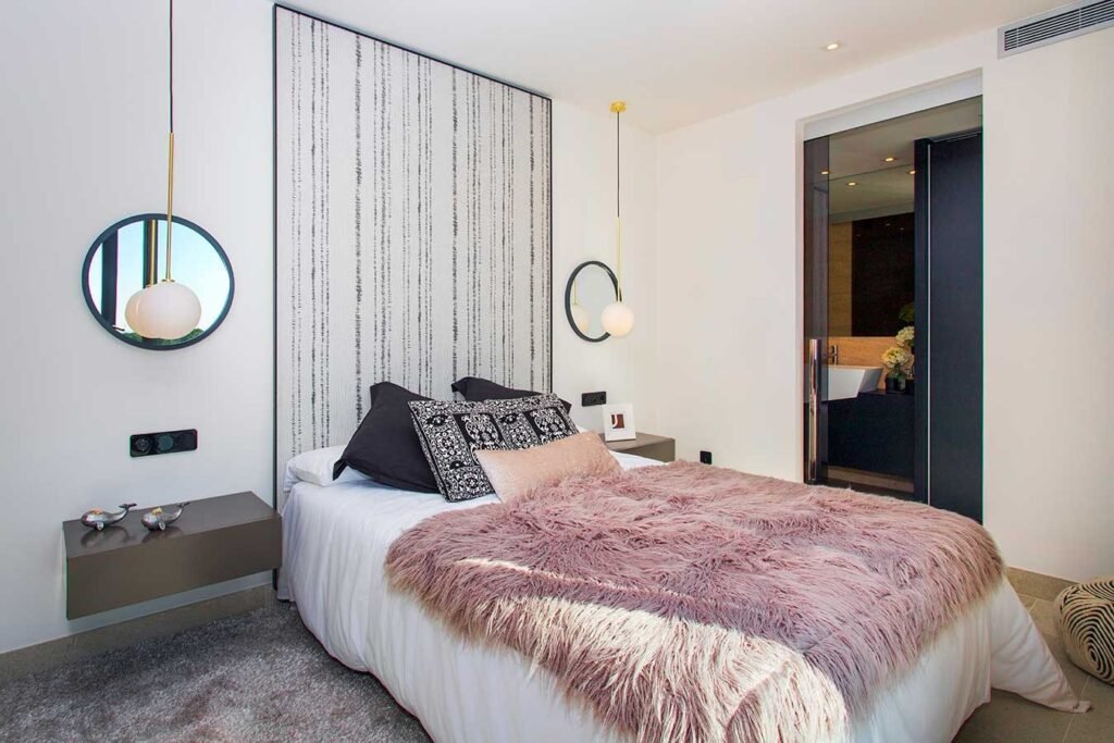 Elegante dormitorio principal diseñado con un panel frontal de papel pintado texturizado, lámparas colgantes de diseño y tonos cálidos.