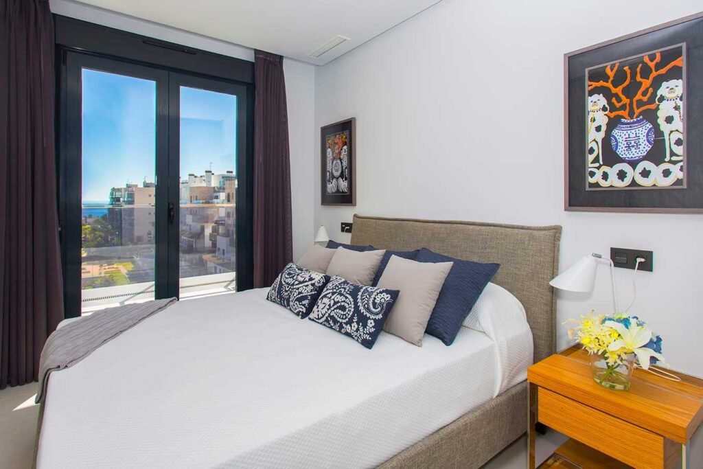 Habitación matrimonial muy iluminada con acceso directo a una terraza exterior, decoración moderna y mesita de noche de diseño amarillo