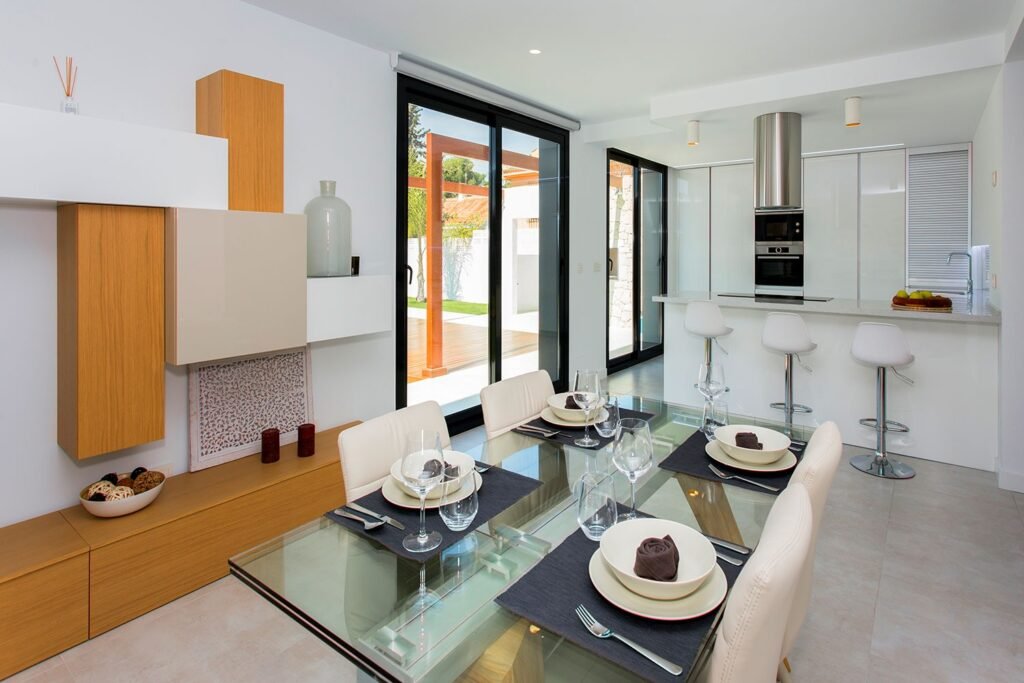 Espacio diáfano que integra salón moderno, zona de comedor y cocina de lujo con isla central y taburetes