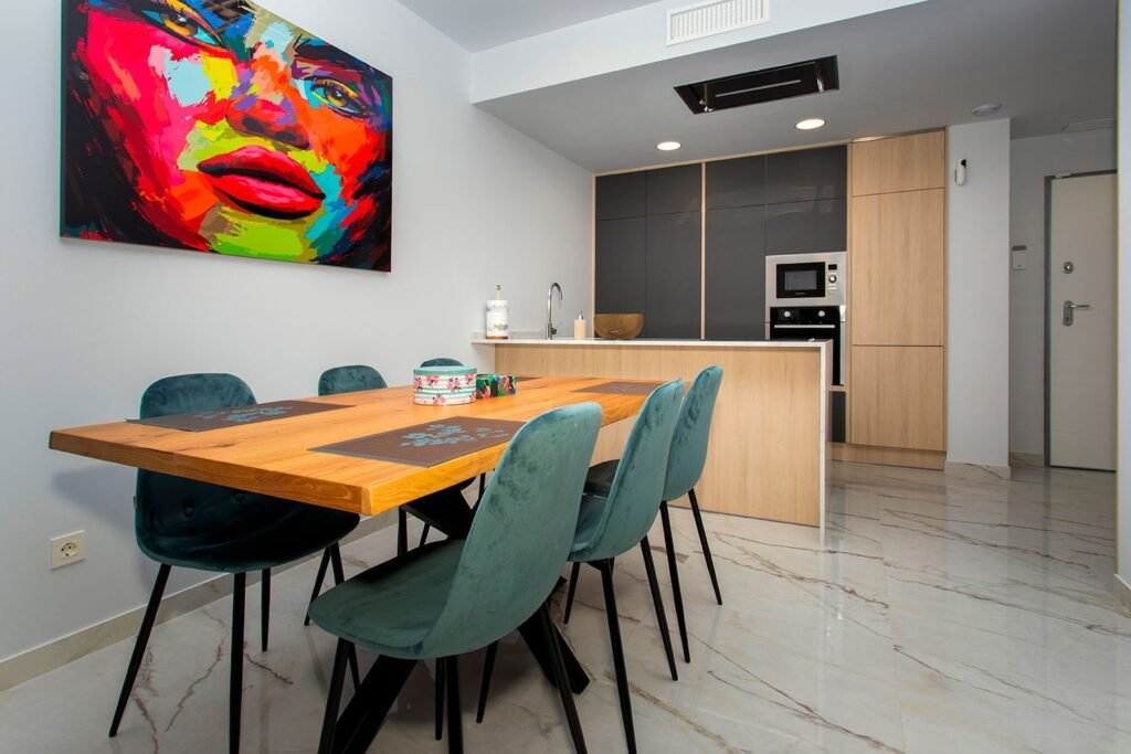Salón comedor contemporáneo con mesa de madera maciza, sillas grises y cuadro colorido de arte moderno en la pared