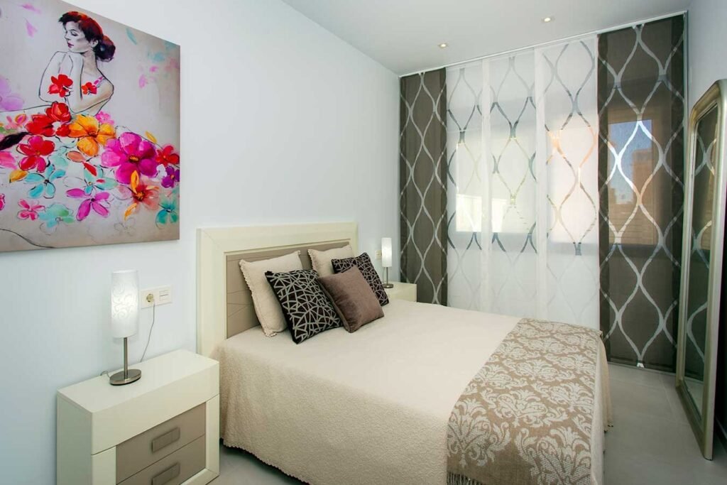 Diseño de dormitorio de matrimonio luminoso decorado con un cuadro colorido sobre el cabecero y mesitas de noche elegantes