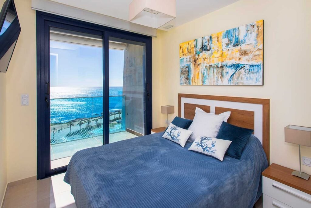 Reportaje fotográfico de un dormitorio moderno con una espectacular ventana panorámica hacia el mar de fondo