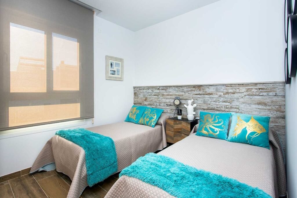 Habitación doble ideal para invitados o niños con dos camas individuales perfectamente vestidas con mantas y cojines azules