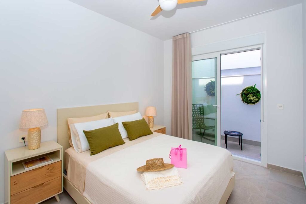 Habitación principal minimalista y muy clara con puerta de cristal corredera hacia una terraza o patio privado
