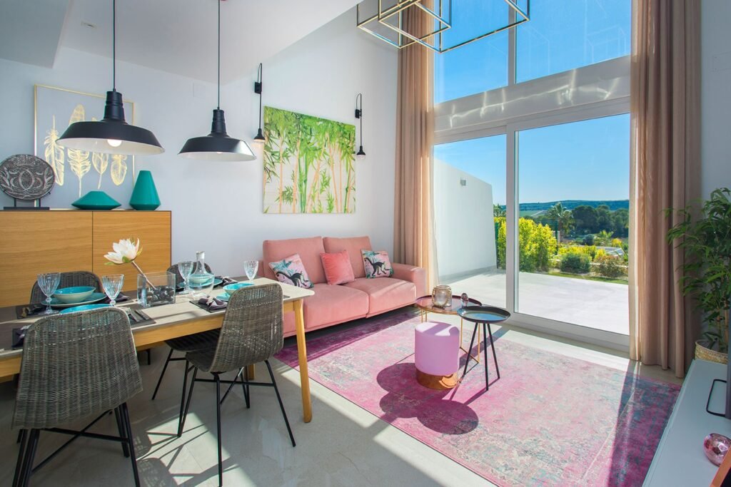 Interiorismo de un salón de lujo muy luminoso gracias a enormes ventanales con vistas al jardín, sofás en tonos neutros y cojines de colores