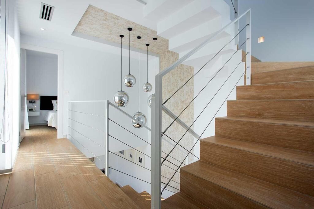 Escalera de madera con barandilla blanca en vivienda diáfana de dos plantas