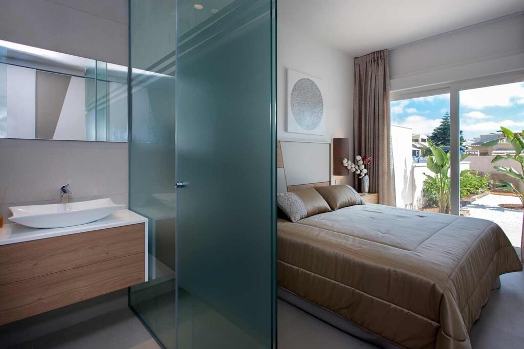 Habitación con cama de matrimonio separada del baño por una mampara de cristal