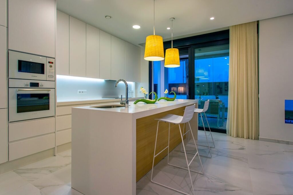 Cocina blanca con barra americana de madera y taburetes altos amarillos