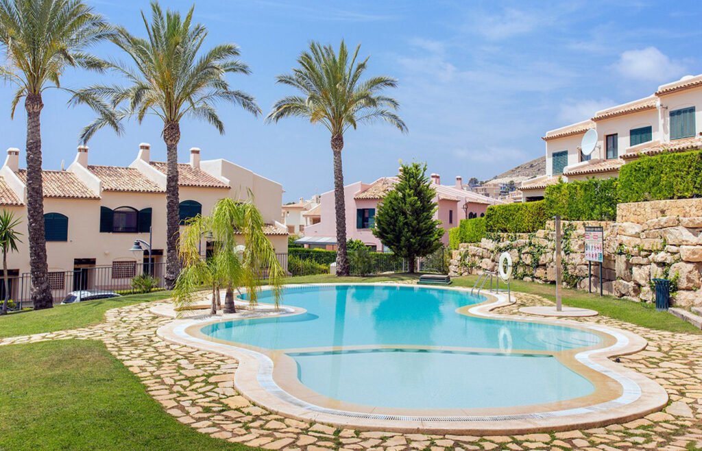 Piscina comunitaria rodeada de césped y viviendas unifamiliares adosadas