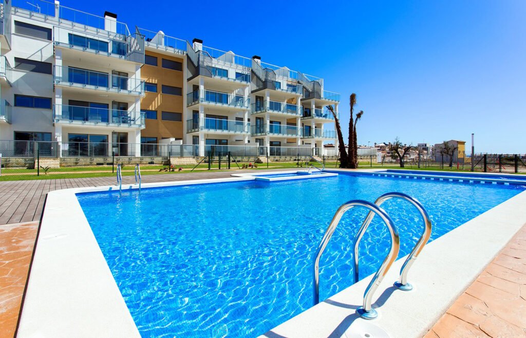 Piscina comunitaria frente a edificio residencial de apartamentos bajo cielo despejado