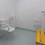 Baño adaptado con barras de apoyo en clínica – fotografía profesional de interiores sanitarios
